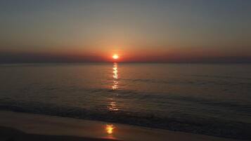 Um pôr do sol sobre um mar calmo com ondas suaves.