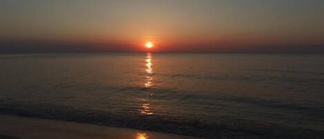 A sunset over a calm sea with gentle waves.