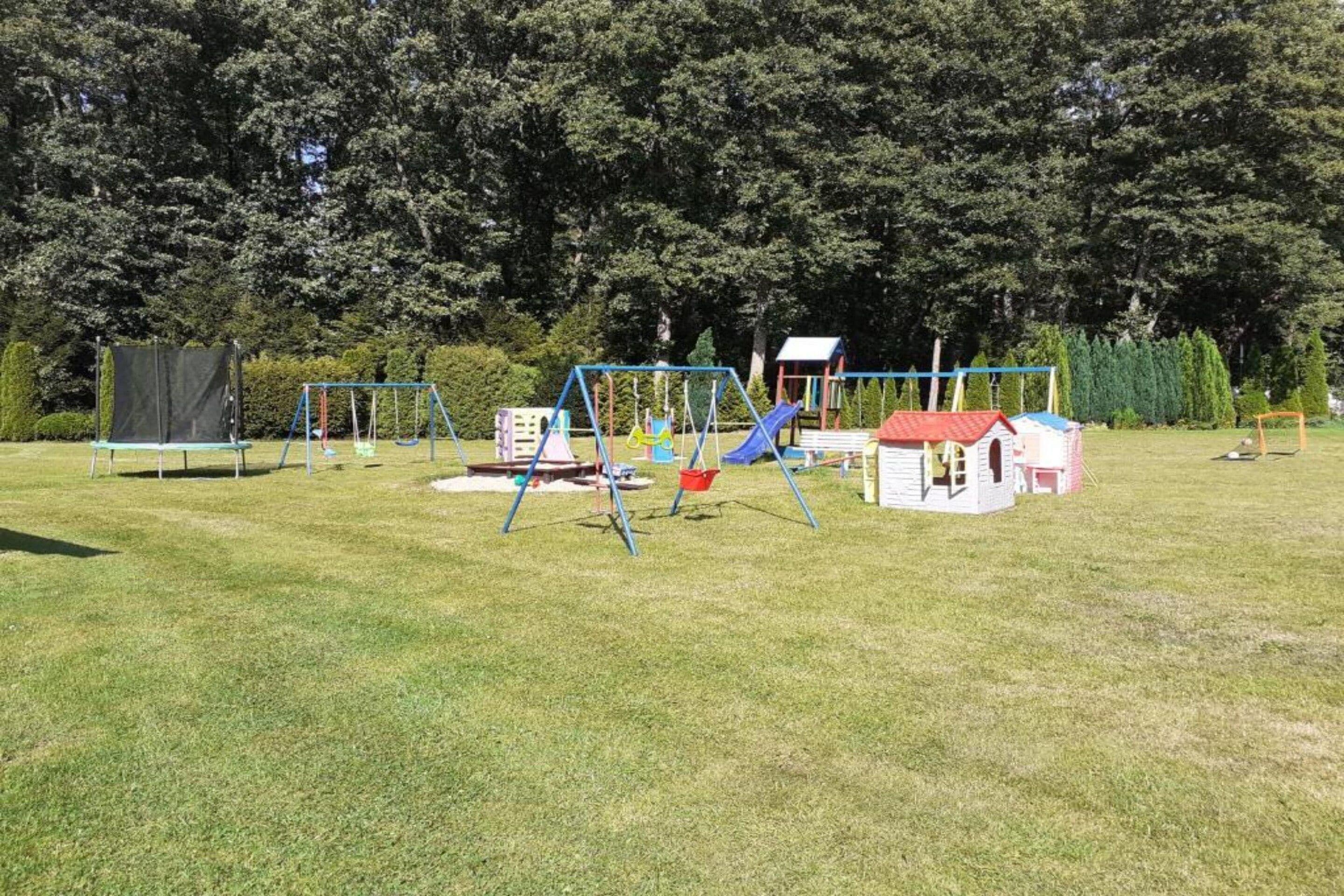 Leikkikenttä, jossa on keinut, liukumäki ja pieni leikkimökki.