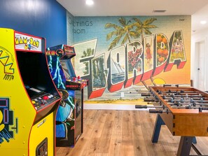 Una habitación con mesa de fútbol, juegos de arcade y un mural con la palabra 'TERRIDA'.