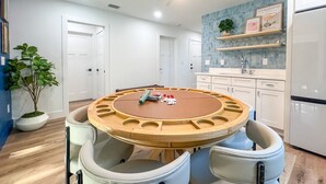 Eine moderne Küche mit weißen Schränken, einer blauen Spritzschutzwand und einem runden Esstisch aus Holz mit Stühlen.