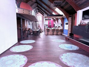 A spacious interior with a central island bar, high ceilings with exposed beams, and patterned floor mats.