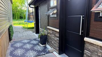 A modern house with a black door, a stone wall, and a patterned rug.