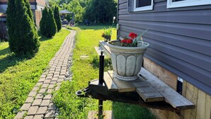 Un chemin pavé mène à une maison où se trouve un pot de fleurs posé sur un banc en bois.