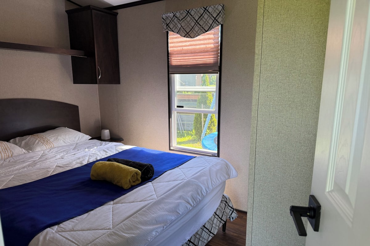 A bedroom with a bed, a window, a door, and a wall-mounted cabinet.