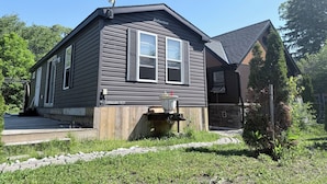 A two-story house with a dark siding exterior, a front porch, and a small garden area. - Garden Resort of Niagara Retreat Center  (Niagara Falls)