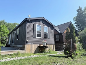 A two-story house with a dark siding exterior, a front porch, and a small garden area. - Garden Resort of Niagara Retreat Center  (Niagara Falls)