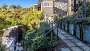 A residential property with a stone staircase, wooden fence, and lush greenery. - Miro Ridge in Palm Beach (Waiheke Island)