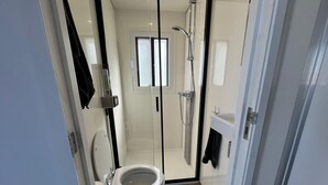 Un baño moderno con inodoro, ducha y mampara de vidrio.