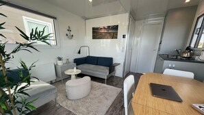 Una sala de estar moderna con un sofá, una mesa redonda, una mesa de comedor y una zona de cocina.