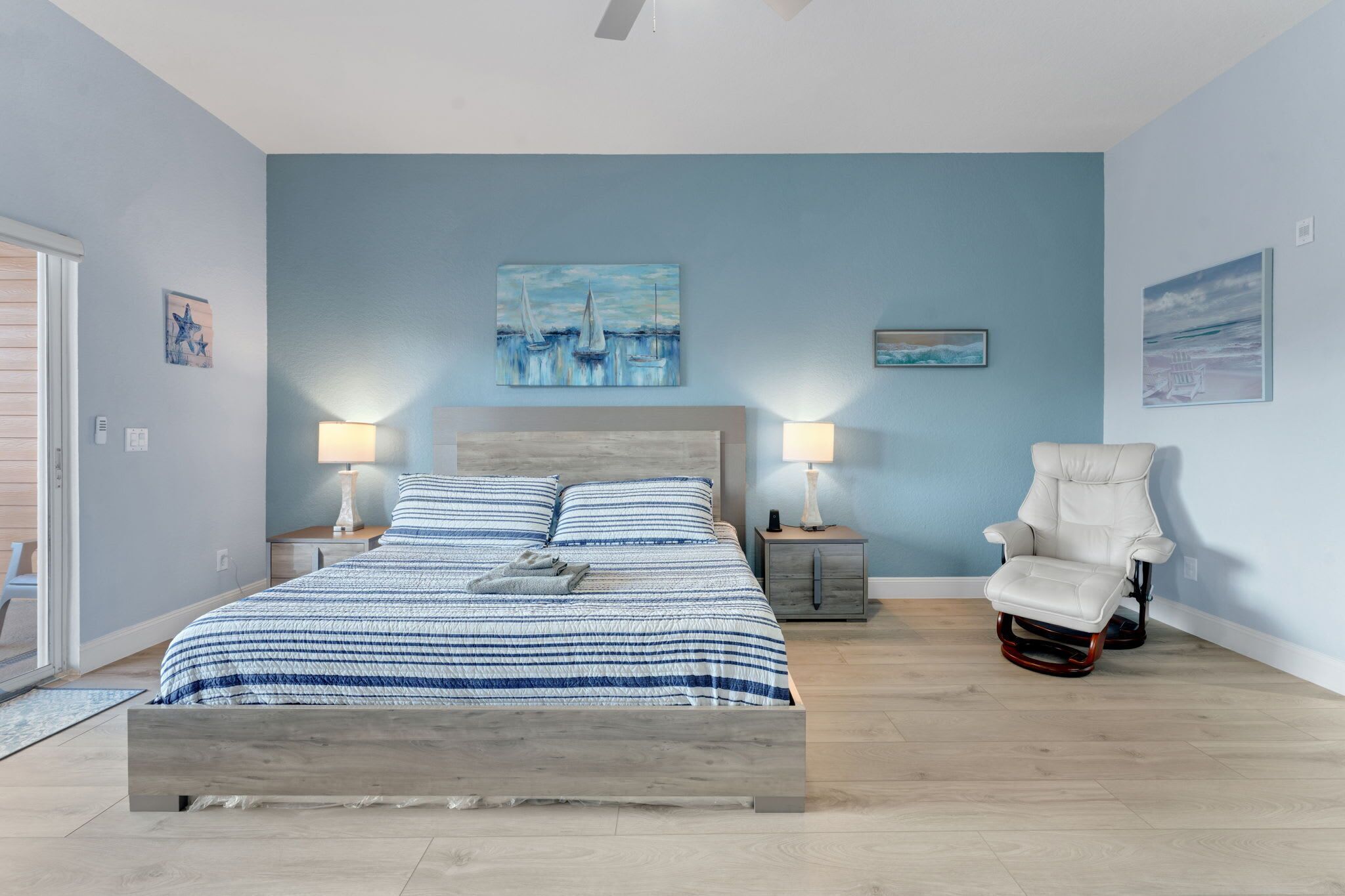 A bedroom with a bed, bedside tables, a chair, and artwork on the walls.