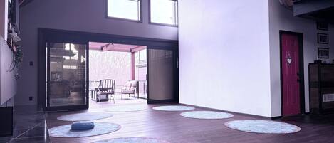 A spacious interior with a high ceiling, large windows, and a red door.
