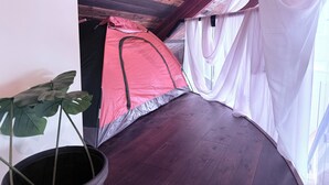 A room with a wooden ceiling, a bed with a red canopy, a potted plant, and sheer curtains. - 8 Tents at Niagara Retreat Center (Niagara Falls)