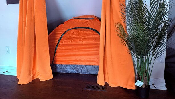 A tent-like structure with orange fabric, a potted plant, and a wooden floor. - 8 Tents at Niagara Retreat Center (Niagara Falls)