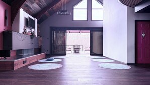 A spacious interior with a high ceiling, wooden beams, a large sliding glass door leading outside, and a red door. - 8 Tents at Niagara Retreat Center (Niagara Falls)