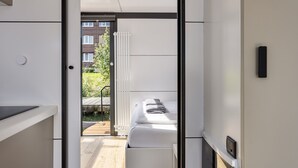 Une chambre moderne avec un lit, un radiateur blanc et une vue sur un jardin.