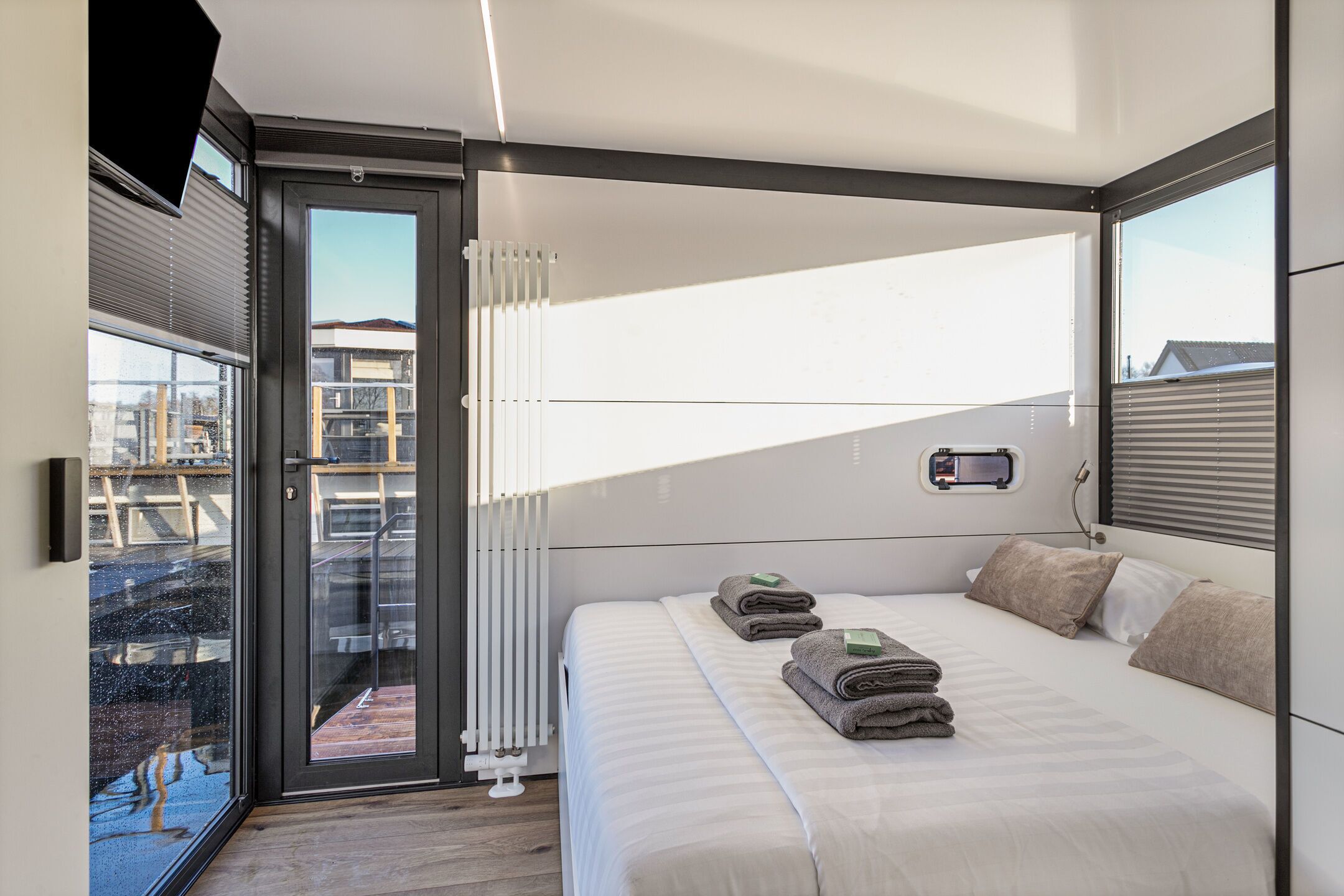 A modern bedroom with a bed, a window, and a view of the outside.