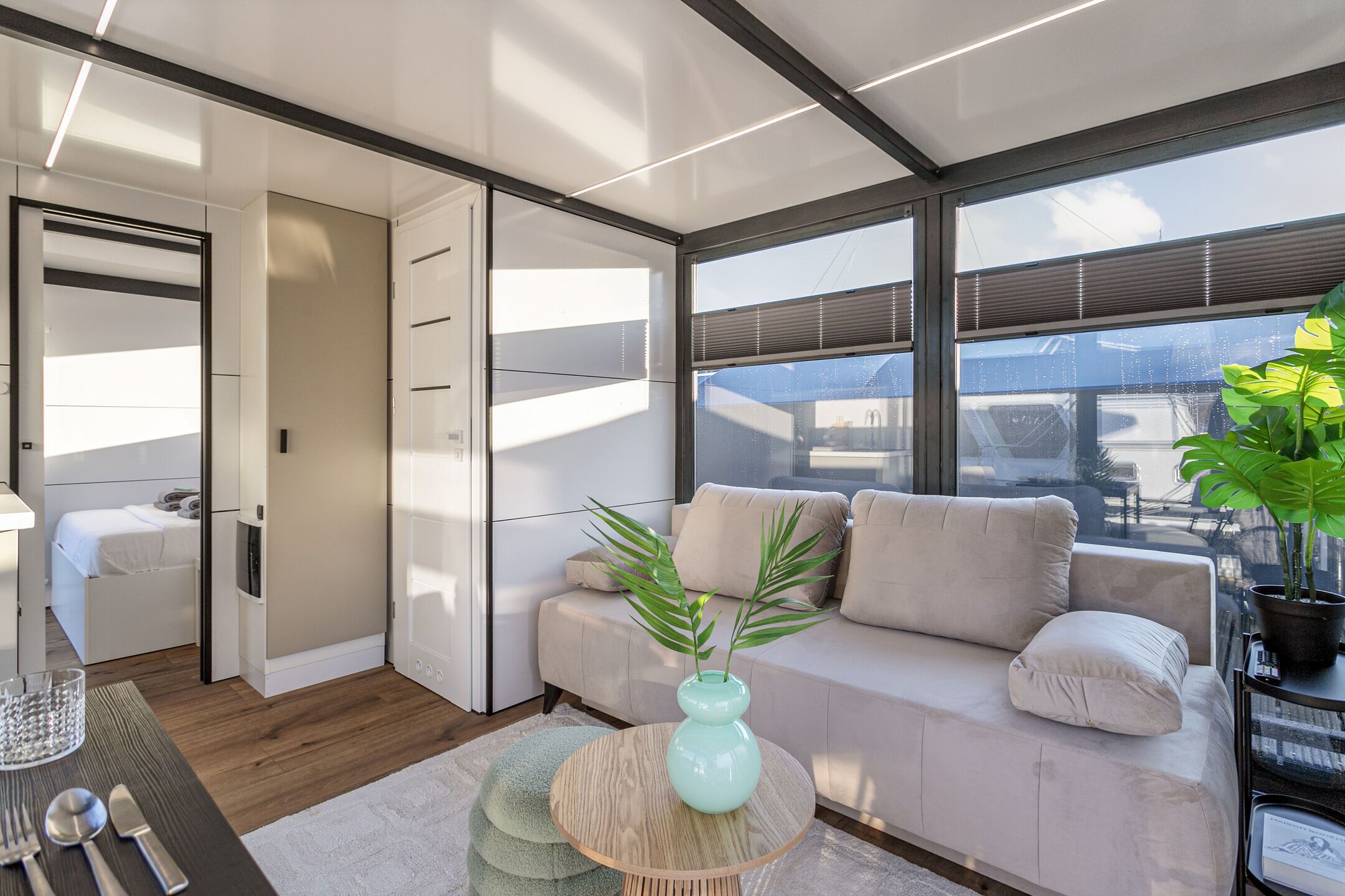 A modern interior with a sofa, a dining table, and a plant.