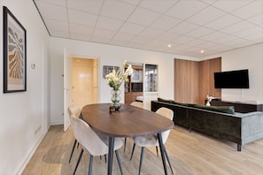 Un salon moderne comprenant une table à manger, des chaises, un canapé et un téléviseur à écran plat.