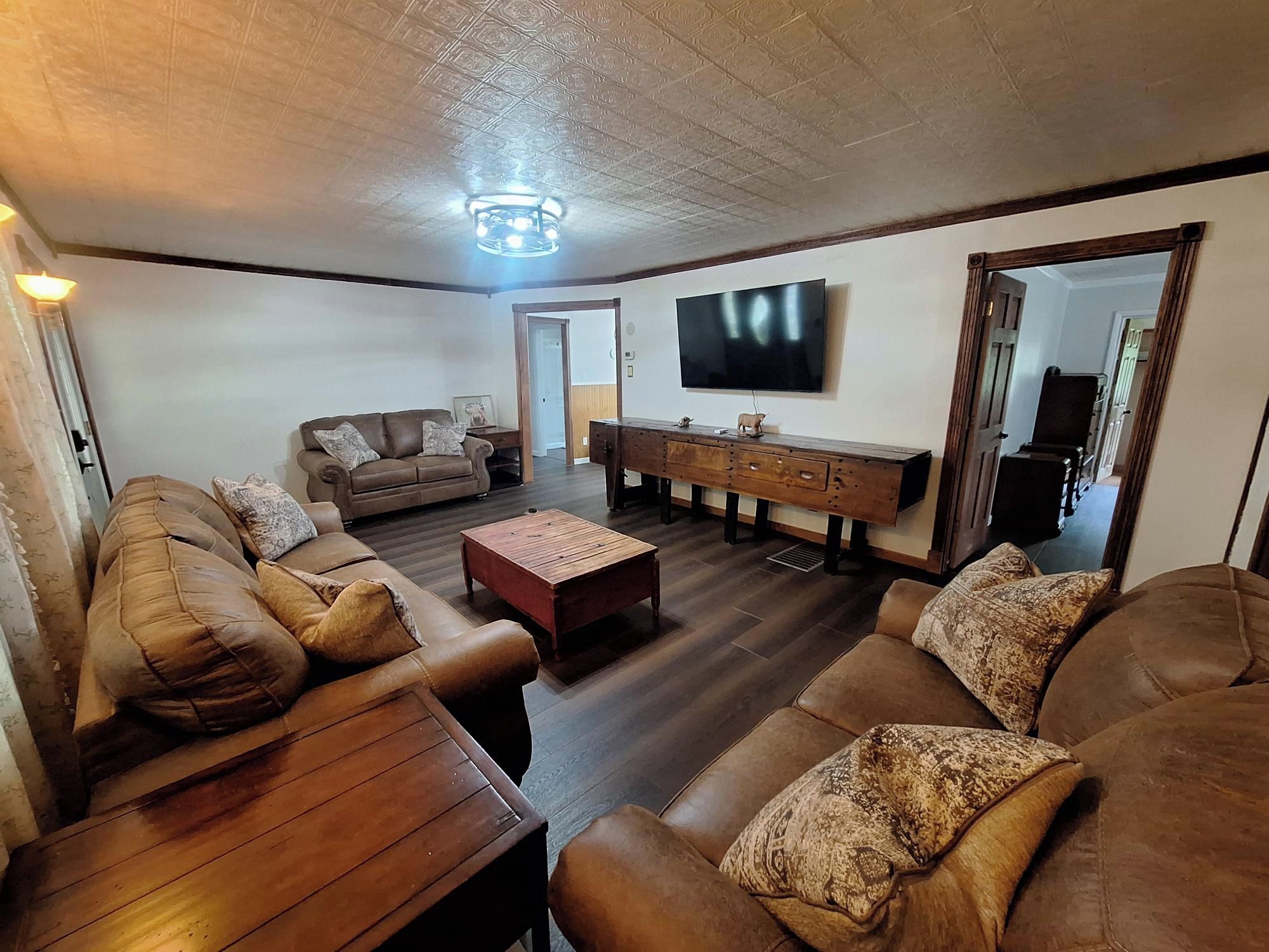 Una sala de estar con un conjunto de sofá, una mesa de centro y un televisor montado en la pared.
