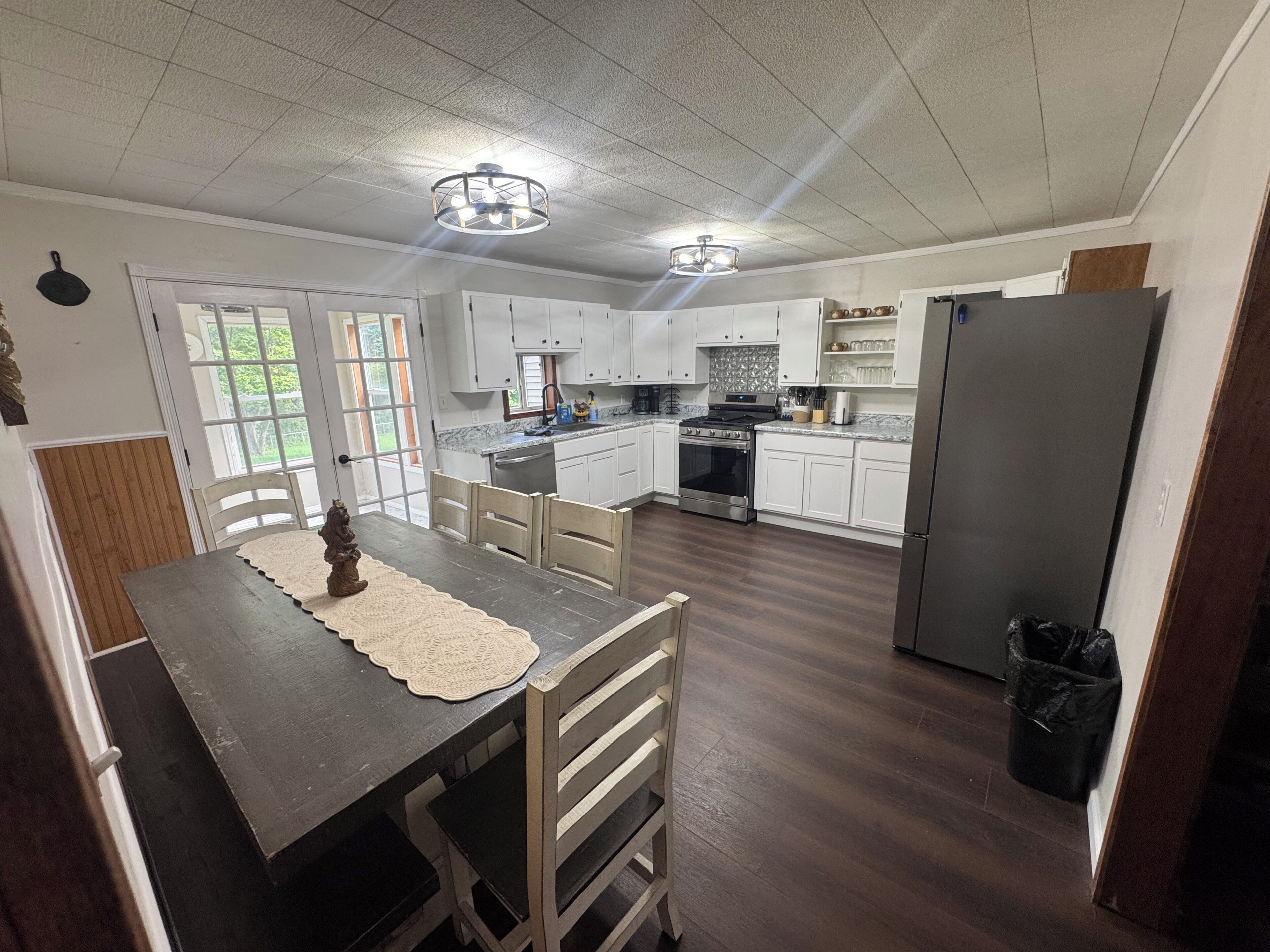 A kitchen with white cabinets, a wooden dining table, and a black refrigerator.