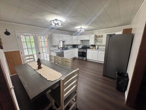 A kitchen with white cabinets, a wooden dining table, and a black refrigerator.