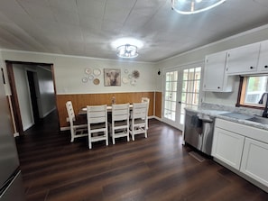 A kitchen with white cabinets, a stainless steel sink, and a window with a view of greenery.