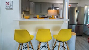 A modern kitchen with a bar area, a stainless steel refrigerator, and a no-smoking sign.