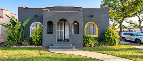 A two-story house with a stucco exterior, a front porch, and a well-maintained lawn.