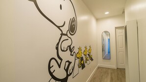 A hallway with a wall mural of Snoopy and a mirror reflecting the room.