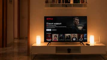 Un televisor de pantalla plana montado en la pared con la interfaz de Netflix mostrando 'The Night Agent'.