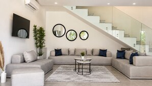 A modern living room with a sectional sofa, a coffee table, and a staircase with glass railings. - Sandra 31  (La Marsa)