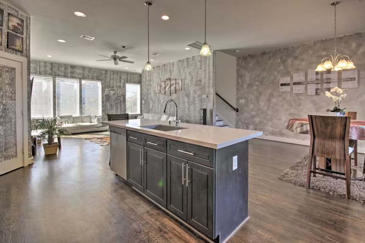 A modern kitchen with a central island, dark cabinetry, and pendant lighting.