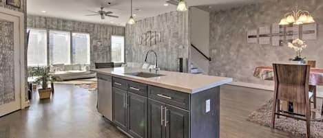 A modern kitchen with a central island, dark cabinetry, and pendant lighting.