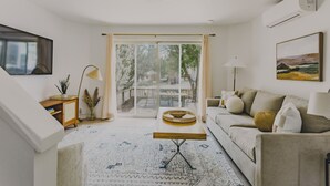 Un salón con sofá, una mesa de centro, televisión y un ventanal con vistas al exterior.
