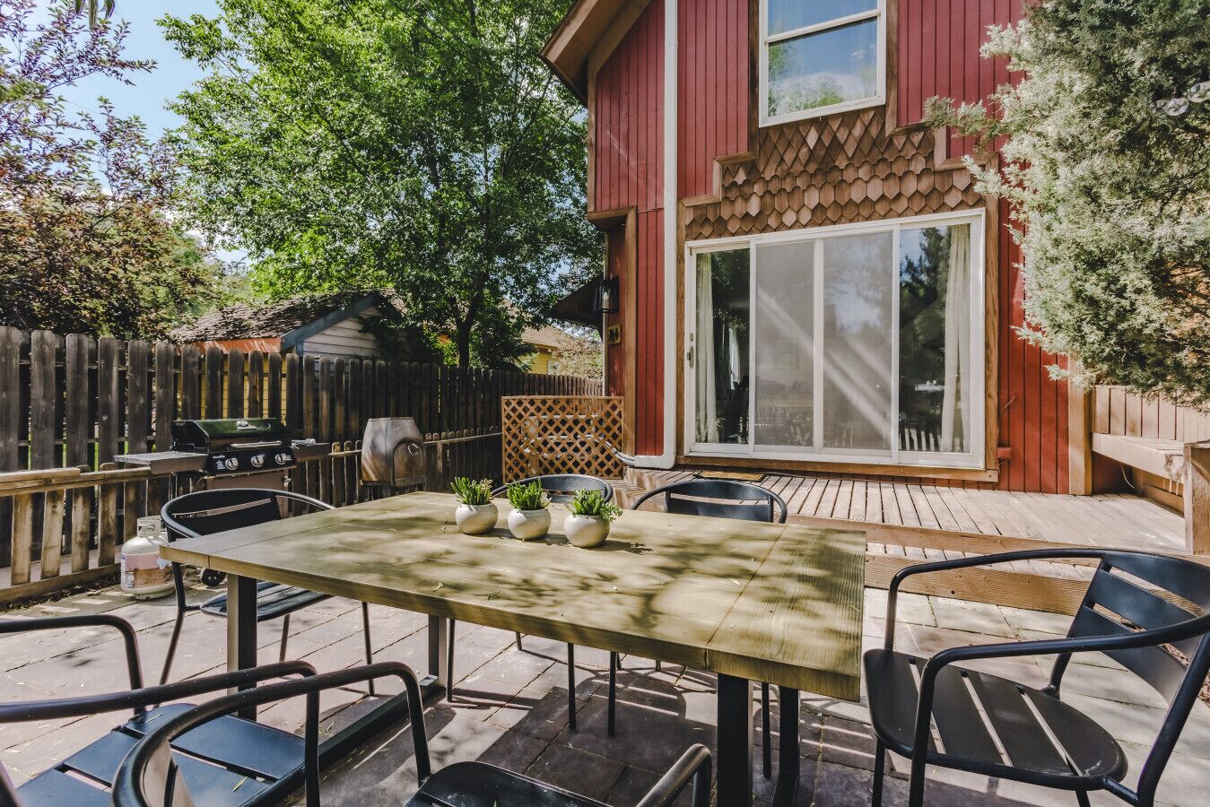 An outdoor patio with a table and chairs, a barbecue grill, and a wooden deck.