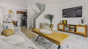 Una sala de estar moderna con sofá, mesa de centro, televisor y una escalera.