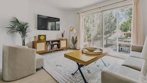 Una sala de estar con sofá, una mesa de centro, televisor y estantería.