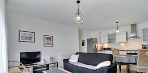 Ein modernes Wohnzimmer mit Sofa, Fernseher und Essbereich mit Stühlen.