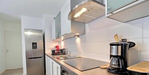 Eine moderne Küche mit einem Edelstahl-Kühlschrank, einer Kaffeemaschine und einer schwarzen Induktionskochplatte.