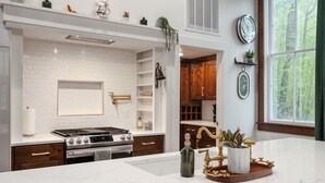 A modern kitchen with white subway tiles, a gas stove, a sink, and wooden cabinets. - Schoolhouse | Fenced Yard | Family & Dog Friendly (Traverse City)