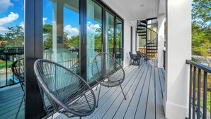 A balcony with glass doors, a spiral staircase, and two black chairs. - 🦩Book Me Baby! Sun Of A Beach in Santa Rosa Beach~Golf Cart Included🦩 (Santa Rosa Beach)