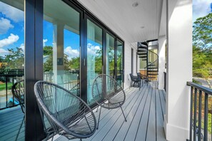 Un balcon avec des portes vitrées, un escalier en colimaçon et deux chaises noires.
