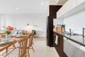 A modern kitchen with a built-in oven, a sink, and a countertop with kitchen utensils. - Stylish Sydney 2BR UNSW, Beach, Parking, Sleeps 6 (Kingsford)