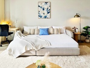 A bedroom with a bed, a desk, a chair, a lamp, and a potted plant. - Stylish Sydney 2BR UNSW, Beach, Parking, Sleeps 6 (Kingsford)