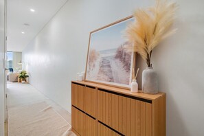 Um corredor com um aparador de madeira, um quadro emoldurado e objetos decorativos.