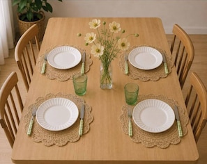 A wooden dining table with four plates, green glasses, and a vase with flowers. - Stylish Sydney·2BR·UNSW, Beach, Parking, Sleeps 6 (Kingsford)