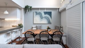 A modern kitchen with a herringbone tile backsplash, a wooden dining table with black chairs, and a large abstract painting above the table. - Biggera Breeze Retreat (Biggera Waters)