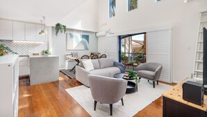 A modern living space with a kitchen, dining area, and a balcony with outdoor furniture. - Biggera Breeze Retreat (Biggera Waters)