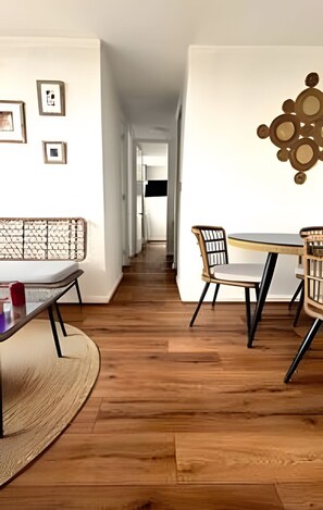 Ein Flur mit Essbereich, der einen runden Tisch, Stühle, eine gewebte Bank und gerahmte Bilder an der Wand zeigt.